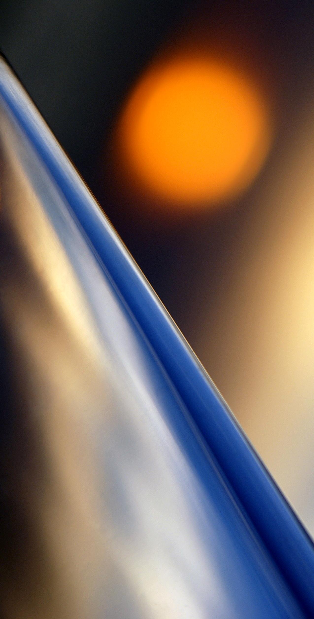 Refraction 1-1, a picture showing a reflection of a orange light in a glass like surface with a blue gradient light reflection in focus