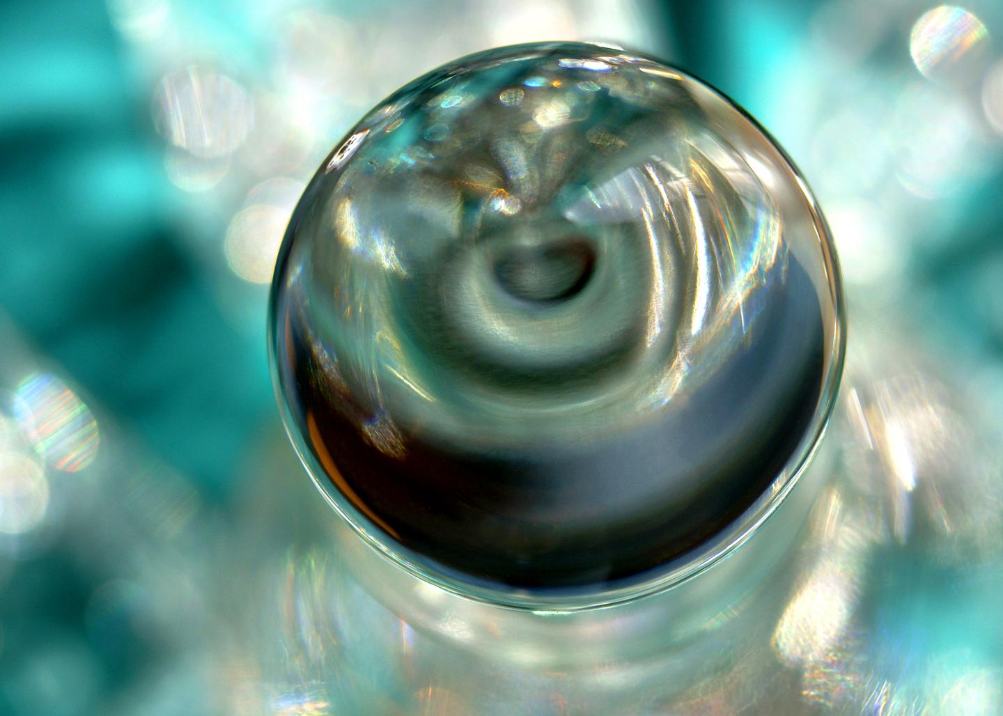 Specular 2-2, a picture with a sphere reflecting light in a turquoise background with specular reflections